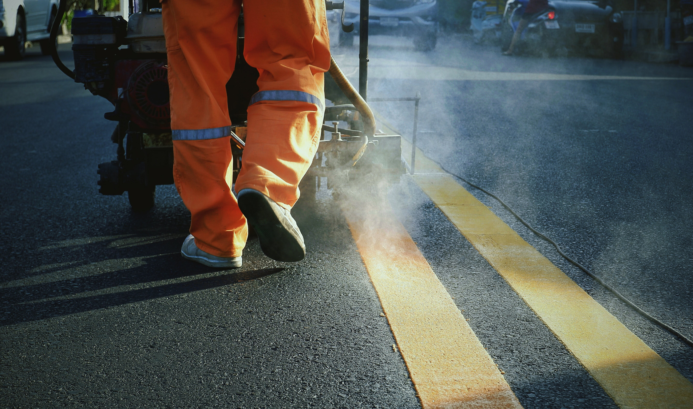 road worker with marking machine painting a double yellow line