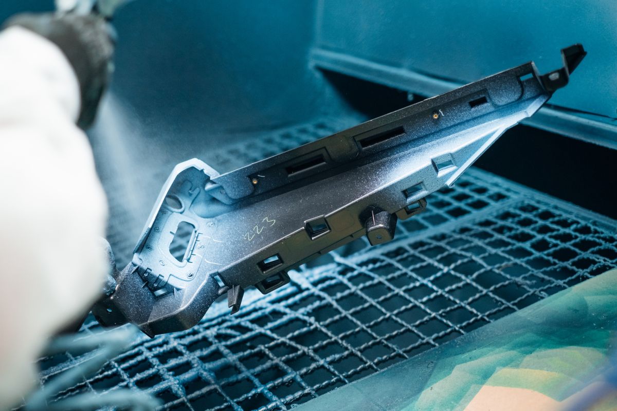 A part being spray painted with a protective coating in an industrial setting Surface finishing process